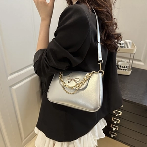Borsa sottobraccio in pelle argento con fiocco dorato e catena indossata da modella