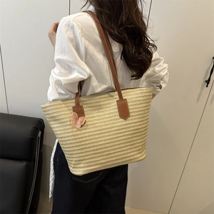Large straw tote bag with brown leather straps and pink lace butterfly charm for beach