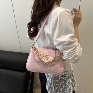 Elegante borsa sottobraccio in pelle rosa con fiocco dorato e catena su modella