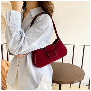 Side view of a vintage burgundy velvet baguette shoulder bag with a bow on a model