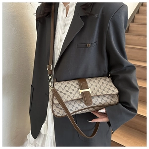 Gros plan du sac baguette monogramme vintage avec boucle H dorée porté par un modèle