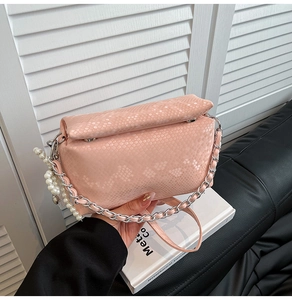 Detail of pink snakeskin embossed handbag with silver chain and white pearl charms