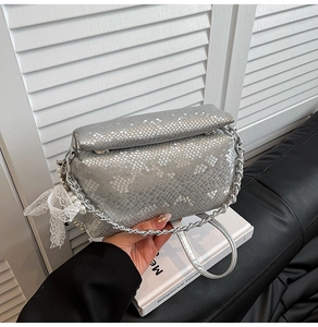 Detail of silver snake skin texture bag with pearl lace charm and metal chain strap
