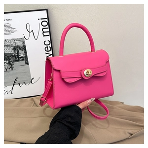 Detail of rose red structured leather handbag with gold metal twist lock and top handle