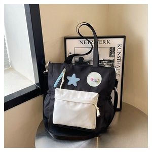 Detail of a nylon star tote bag showing blue star patch and side drawstring design