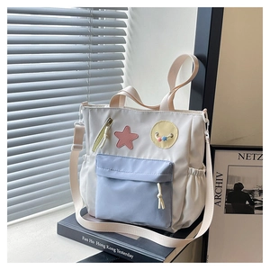 Detail view of water-resistant nylon tote bag with pink star patch and blue front pocket