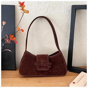Detailed close-up of dark brown suede shoulder bag with elegant bow decoration