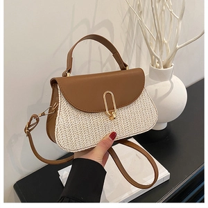 Detail of a brown leather and woven straw crossbody bag with gold metal buckle