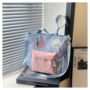 Detail of light blue and pink nylon tote bag with star patch and cartoon badges