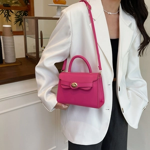 Magenta leather crossbody bag with top handle and gold twist lock in minimalist style