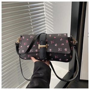 Sac baguette noir avec imprimés nœuds floraux roses et détail de boucle métallique dorée