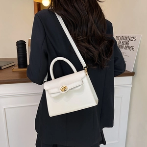 White leather crossbody square bag with gold twist lock and top handle on a model