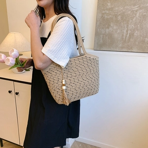 Large beige woven straw tote bag with black polka dots and decorative tassel for beach vacation