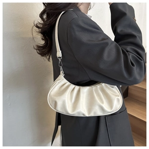 Close-up of cream white pleated half-moon bag with soft leather texture and silver buckle