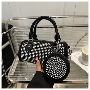 Detailed view of black cylinder bag with sparkling silver rivets and small round pouch
