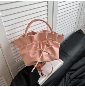 Detail of pink ruffled cloud bag with decorative bow and rounded top handle