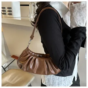 Detail view of the brown cloud-shaped pleated shoulder bag with soft leather texture