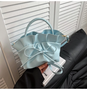 Close-up of light blue cloud handbag featuring pleated ruffles and decorative bow detail