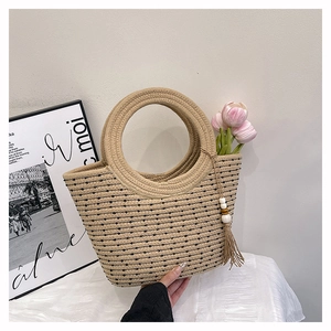 Macro detail of hand-woven straw tote bag with black dots, round handle and tassel bead