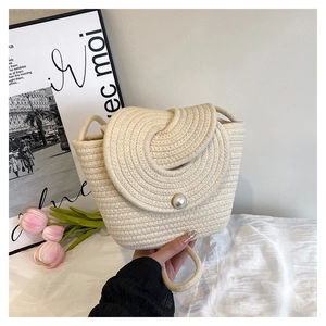 Detailed shot of beige woven cotton rope bag featuring a central pearl buckle on the flap
