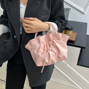 Pink French cloud bag with elegant ruffle top and bow detail shown in lifestyle setting