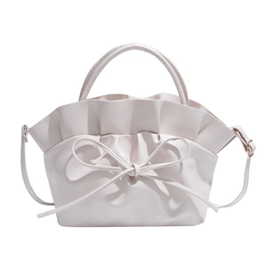 White French cloud crossbody bag with ruffle details and bow tie accent on plain background