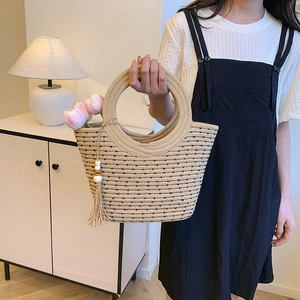Large beige woven straw bucket bag with black polka dots and stylish tassel decor