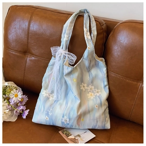 Detail of light blue tote bag with delicate lace flower applique and large bow on fabric