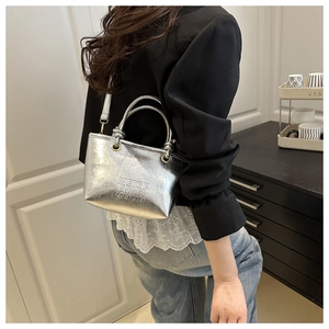 Silver metallic tote bag with embossed text shown in a modern lifestyle setting