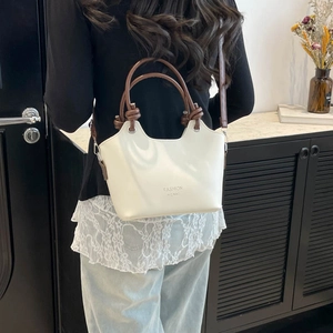 Minimalist beige bucket bag with brown handles and fashion print on a shoulder strap
