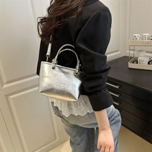 Silver metallic mini bucket bag with embossed lettering and detachable shoulder strap