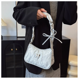Detail of silver metallic butterfly charm and pleated texture on trendy shoulder bag