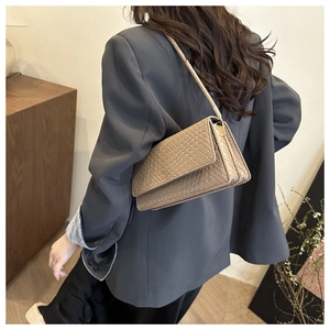 Detail of woven texture hobo bag with gold hardware shown on a model's shoulder