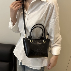 Fashionable black patent leather bucket bag with top handles and adjustable strap