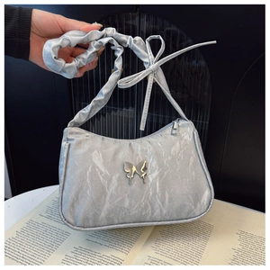Detail of silver pleated shoulder bag with metallic finish and butterfly metal ornament