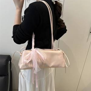 Sac à bandoulière rose clair minimaliste avec nœud en dentelle porté par un mannequin