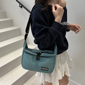 Teal nylon crossbody bag with fashion label and adjustable strap on model