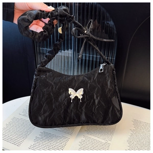 Detail of black pleated shoulder bag with silver metal butterfly and scrunchie strap