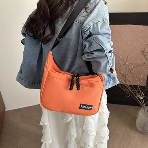 Vibrant orange nylon crossbody bag with black adjustable strap for street fashion style