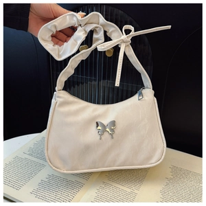 Detail of a creamy white pleated shoulder bag with silver butterfly and bow ribbon straps