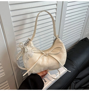 Detailansicht der cremeweißen Hobo-Tasche mit Lederschleife und Perlen-Spitzen-Anhänger