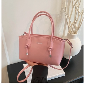 Vue détaillée du sac cabas en cuir mat rose avec lettrage blanc et nœuds décoratifs