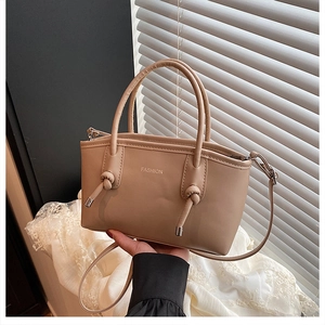 Détail d'un sac à main beige élégant avec poignée nouée et lettrage fashion chic