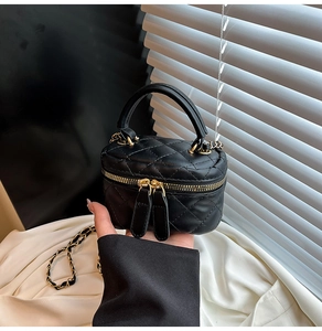 Dettaglio di una mini borsa vanity in pelle nera trapuntata con tracolla a catena oro