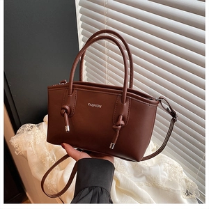 Détail d'un sac en cuir marron avec imprimé FASHION blanc et glands décoratifs