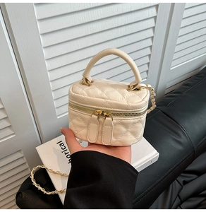 Dettaglio di una mini borsa vanity beige trapuntata con manico e catena dorata