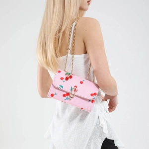 Pink saddle bag with cherry print and golden arch buckle on a clean white background