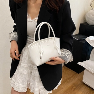 Mini sac à main blanc minimaliste en cuir avec poignées et texte porté par un mannequin