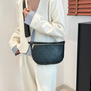 Fashionable black woven crescent crossbody bag with wide strap on white suit model