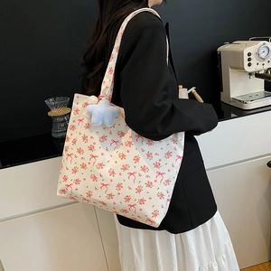 Grand sac cabas en toile à fleurs roses avec breloque étoile bleue porté par un modèle